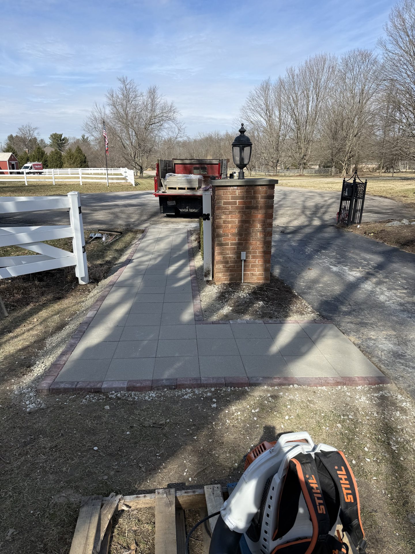 Paver walkway with brick pillars overlooking a pond