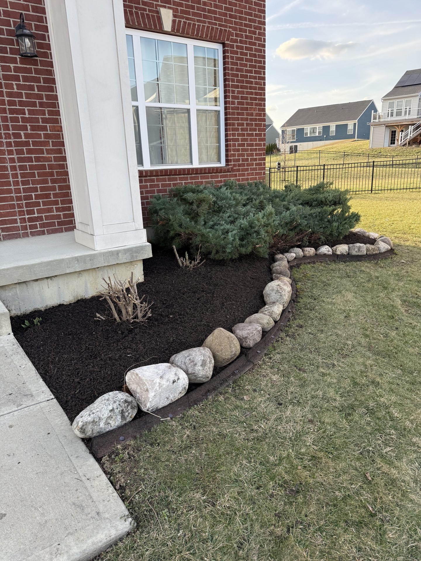 Foundation mulch bed with stone border and shrubs