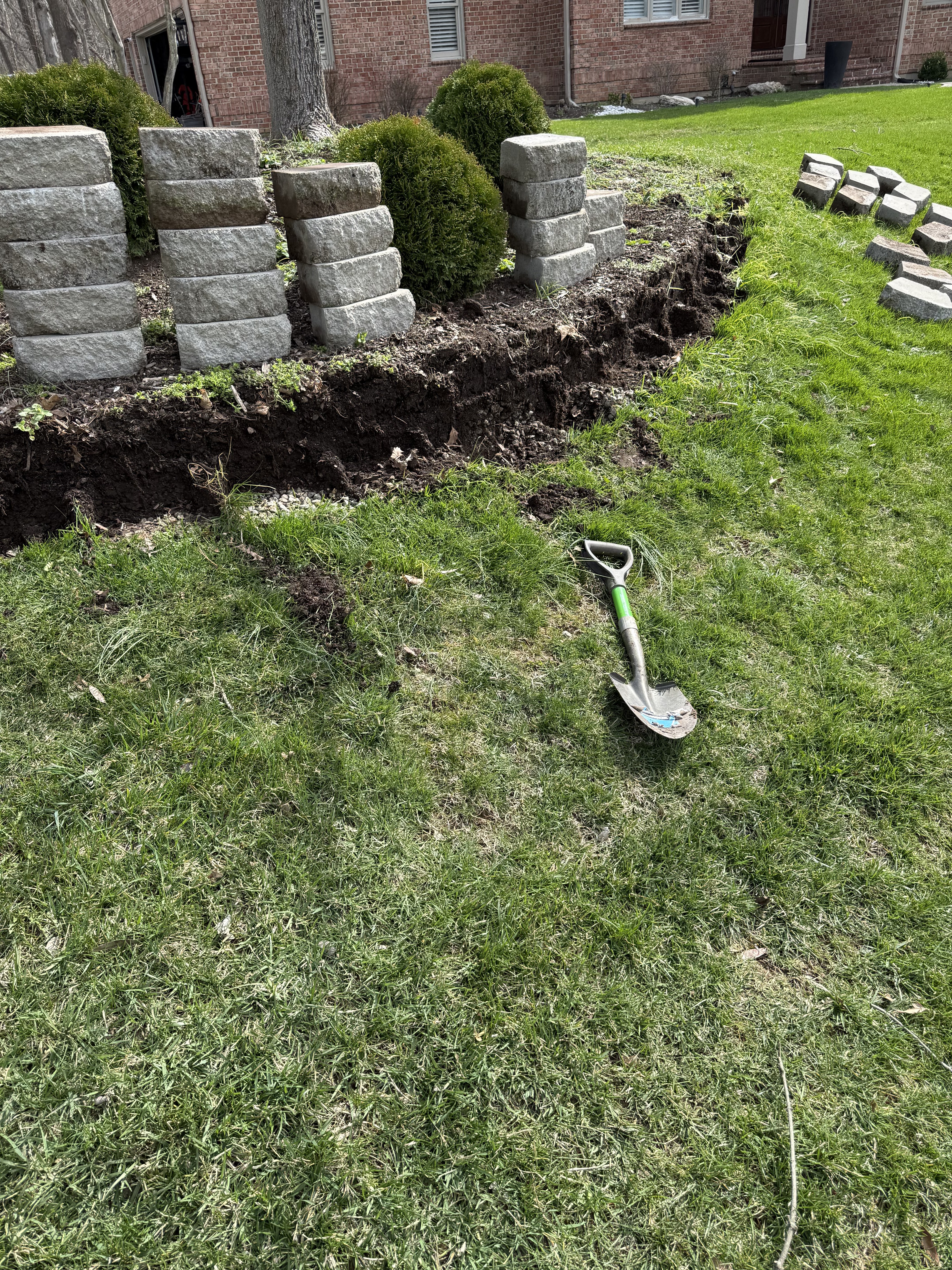 Completed retaining wall with shrubs and black mulch